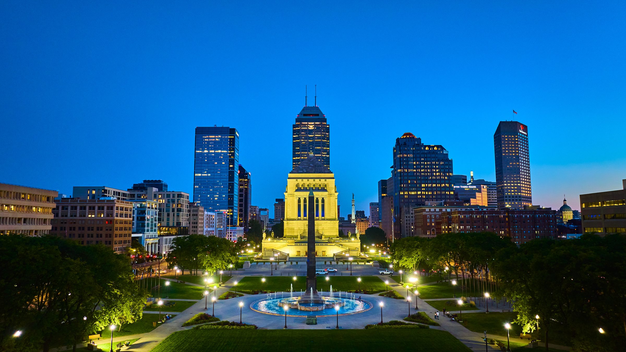 Downtown Indianapolis at dusk, the Indiana World War Memorial lit against the skyline.